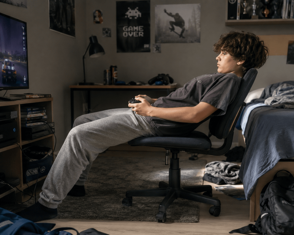 -un adolescent avachi sur son fauteuil face à son écran .